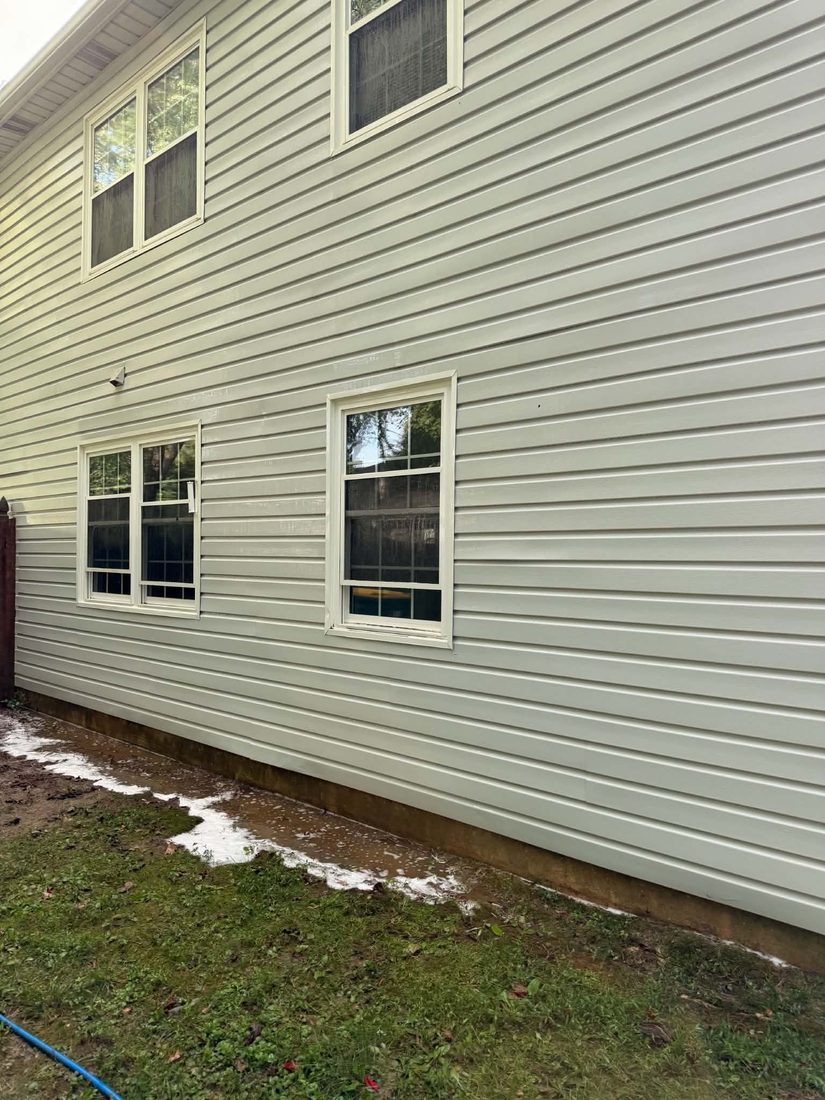 Same siding restored to clean pale green after soft washing