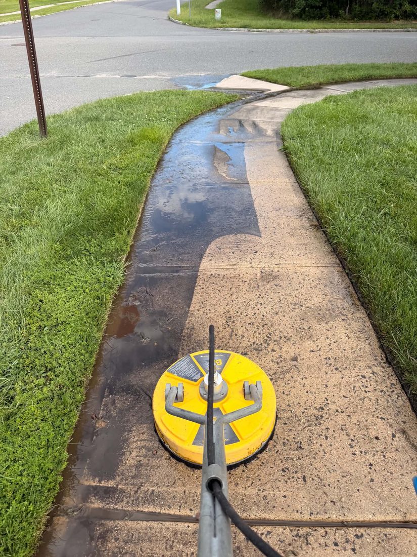 Surface cleaner cutting a clean line down a dirty concrete walkway